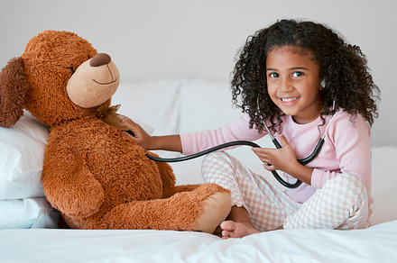 Learning, teddy bear and girl playing with stethoscope, having fun or acting like doctor in bedroom. Portrait, education and child test, check or listening to heartbeat of stuffed animal or baby toy., a Photo by Peopleimages.com