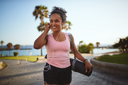 Sporty woman listening to music while carrying her yoga mat