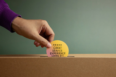 Hand putting Customer Service Experience Review card in box symb