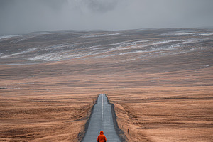 Person walking alone on a long road, a Photo by Pixeness Studio