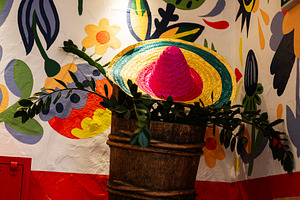 Colorful sombrero in vibrant setting with floral and decorative wall design, a Photo by AS photostudio