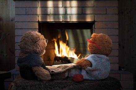 Two toy bear by the fireplace with a newspaper and knitting. The concept of toys as people - an old grandmother and grandfather together.Old age, caring for parents, love of family