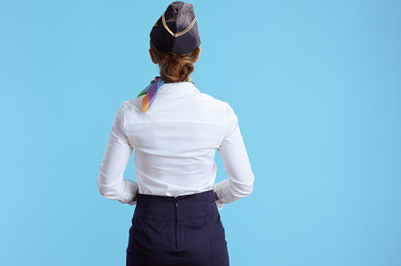 Seen from behind modern female air hostess on blue, a Business Photo by Alliance Images
