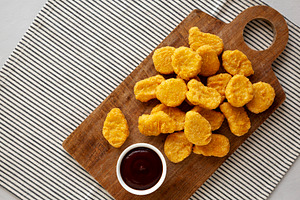 Organic Fried Chicken Nuggets on a wooden board, top view. Copy, a Food & Drink Photo by LiudmylaChuhunova