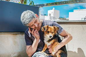 Man with his dog, talking to phone.