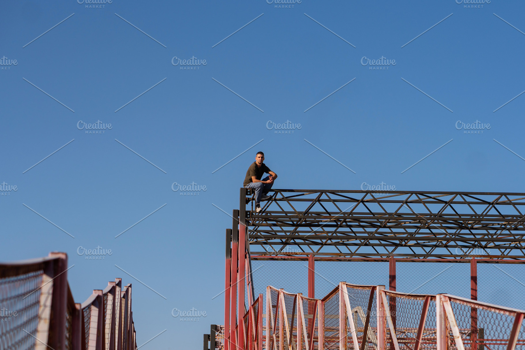 Freerunner rests atop high structure, a Person Photo by Elena Vagengeim