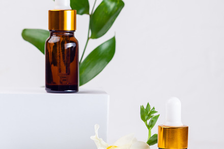 Brown glass pipette bottles with white podium, flowers and green leaves. Organi, a Beauty & Fashion Photo by iuliia_n