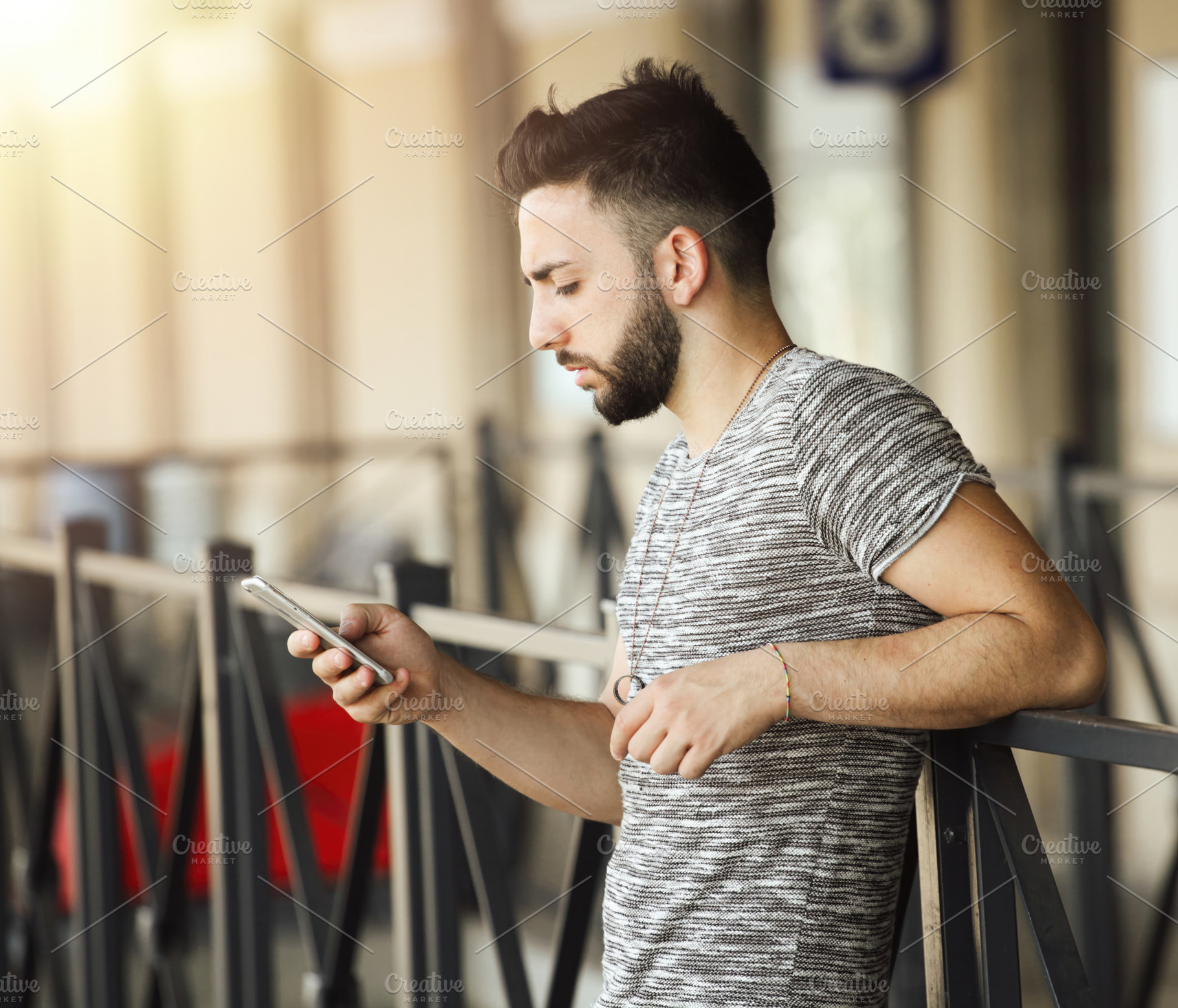 Young man using smartphone while waiting at the train station, an Abstract Photo by Antonio Gravante Market
