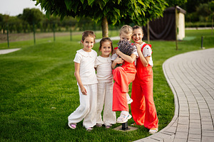 Four girls smiling together outdoors in a green park setting, a Photo by AS photostudio