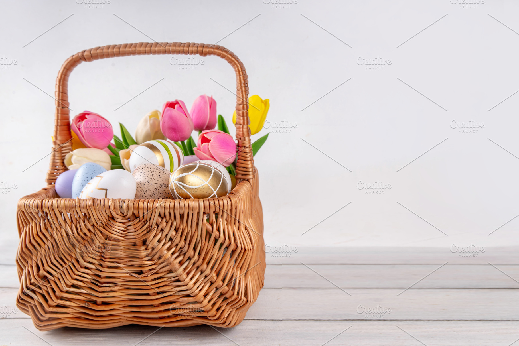 Easter eggs and tulips flowers in basket on wooden background, a Holiday Photo by Rimma