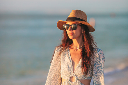 Young beautiful woman at straw hat on the beach at sunset, a Person Photo by travnikovstudio