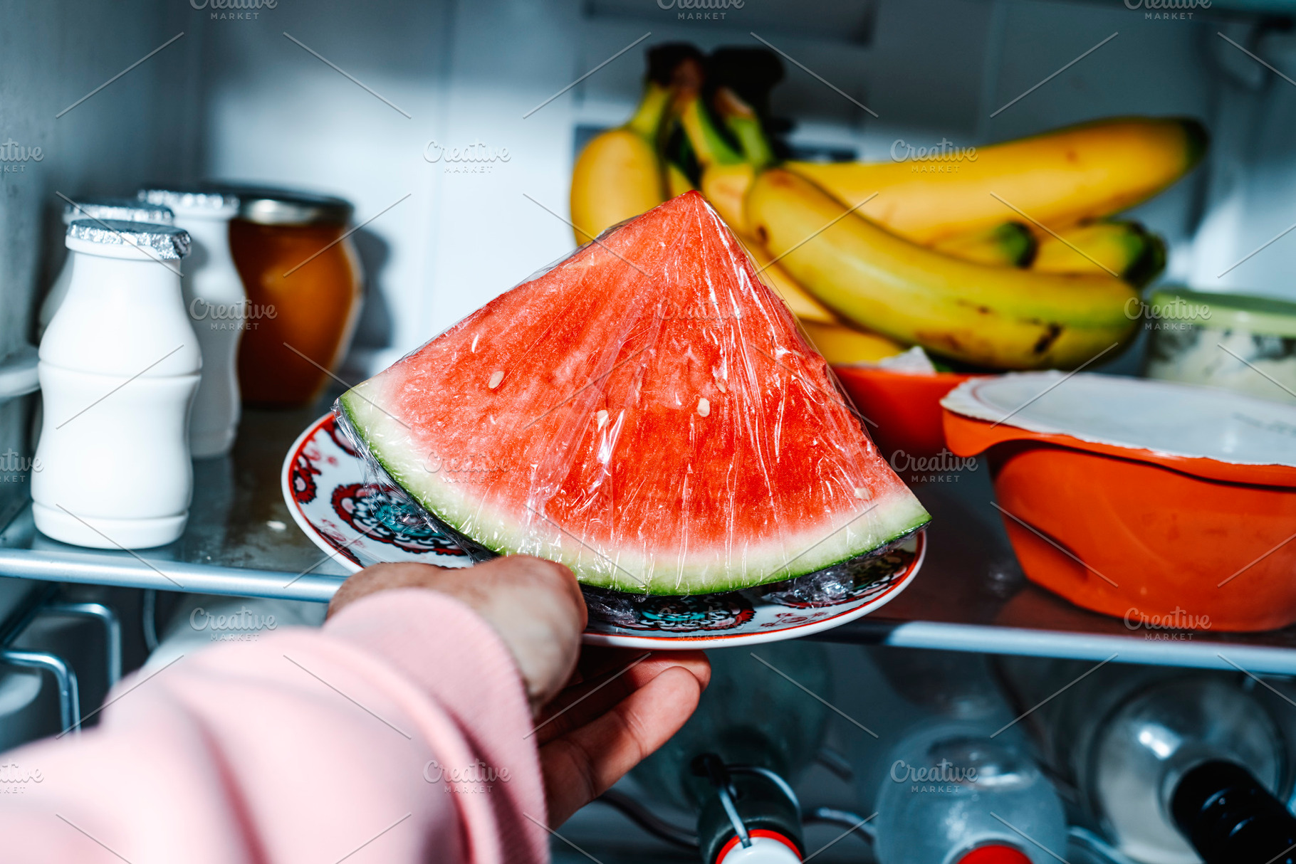 man placing a plate with watermelon in the fridge, a Photo by Nito