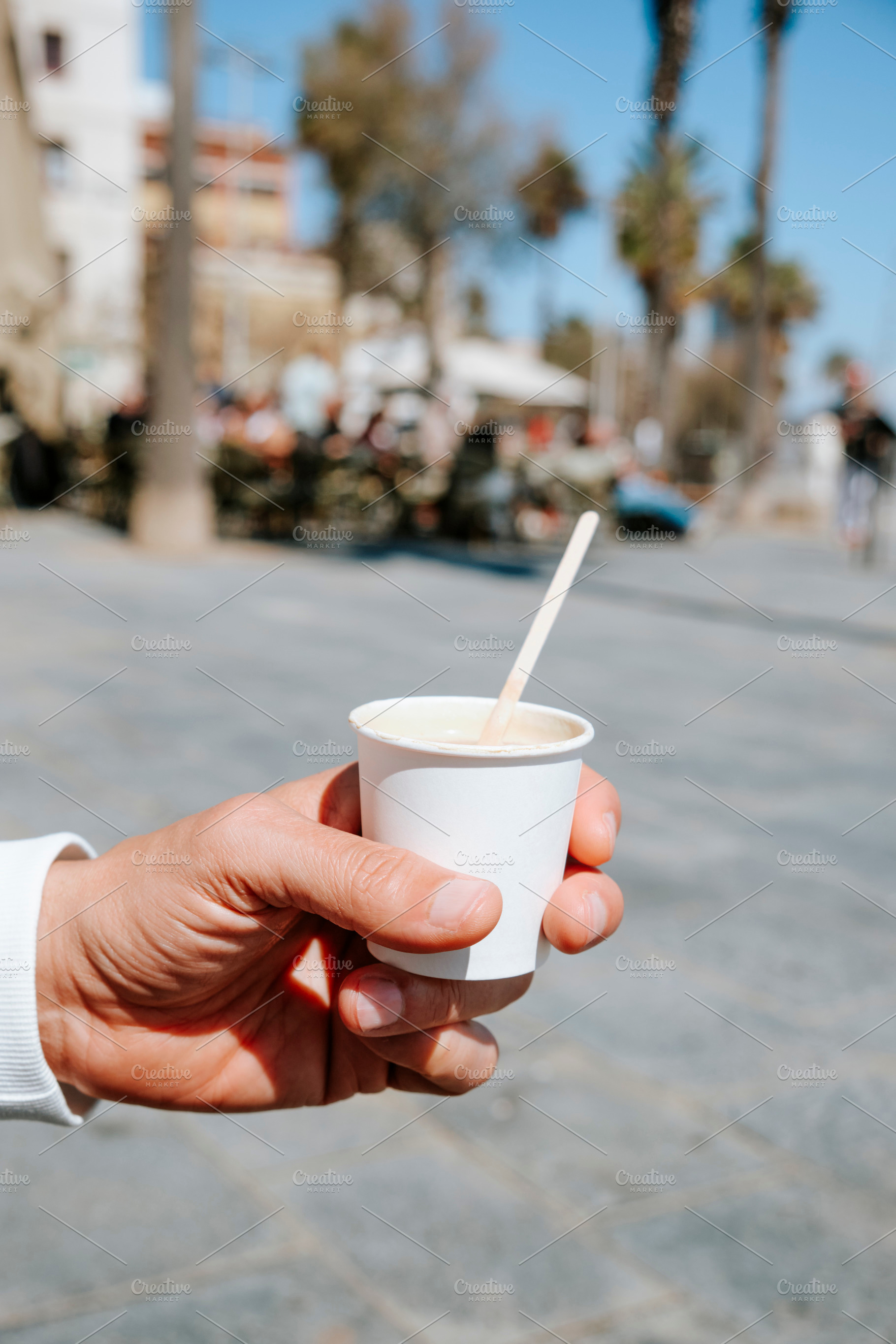 a man holds a cortado in a paper cup, a Photo by Nito