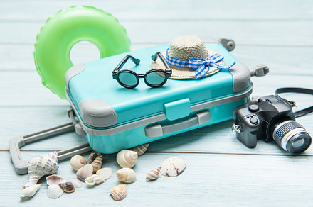 Turquoise suitcase, sunglasses, straw hat, inflatable ring, came