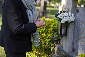 Elderly woman praying at a grave., a Holiday Photo by HalfPoint