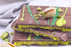 Dubai style milk chocolate bar with pistachio and kadaifi filing, lying on cutt, a Food & Drink Photo by iuliia_n