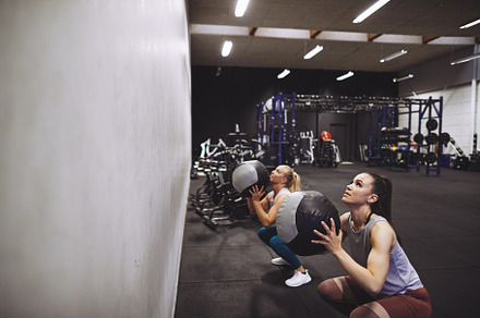 Two women working out with medicine balls at the gym
