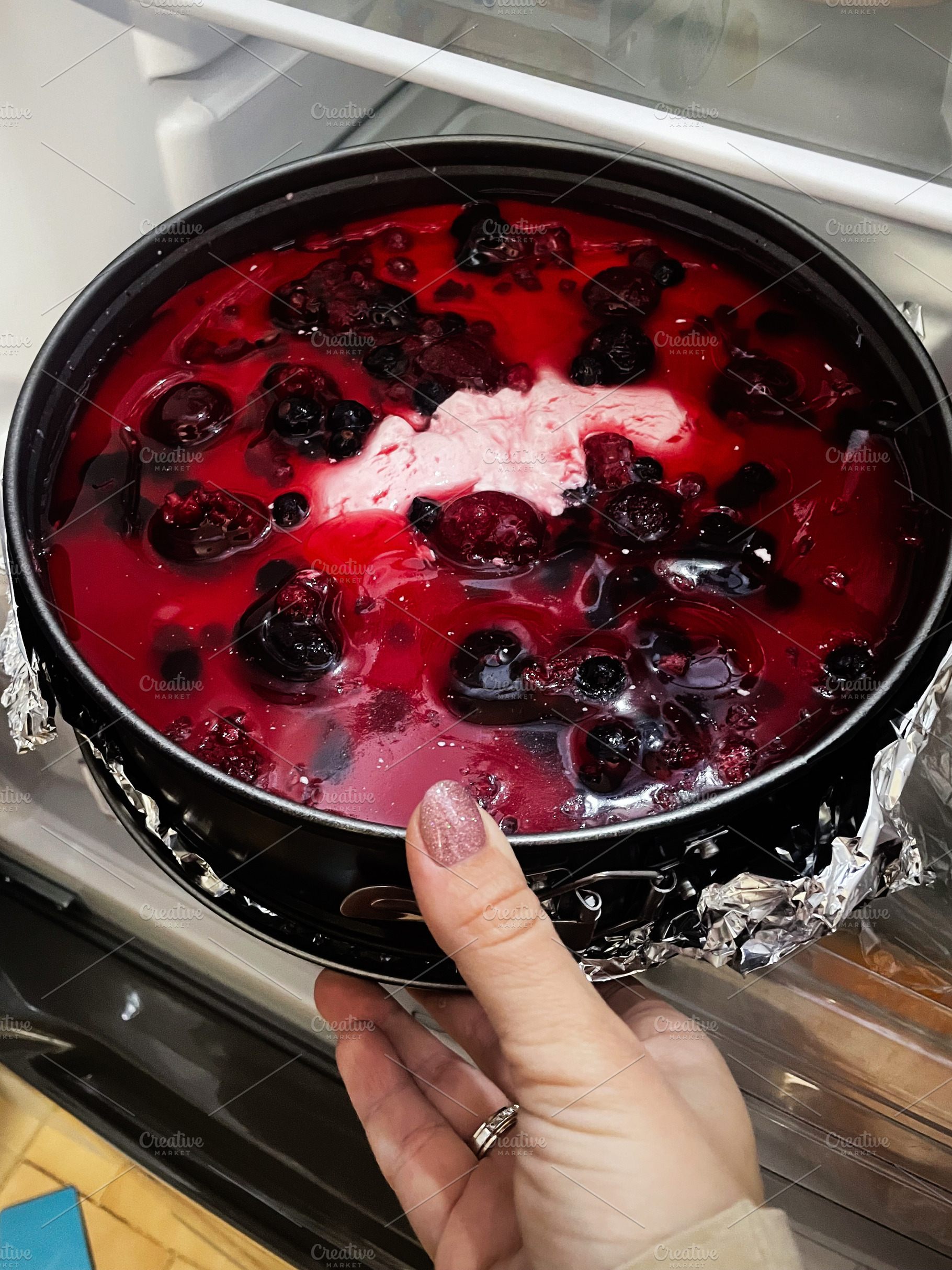 Hand holding a berry jelly dessert in the fridge for chilling, a Photo by AS photostudio
