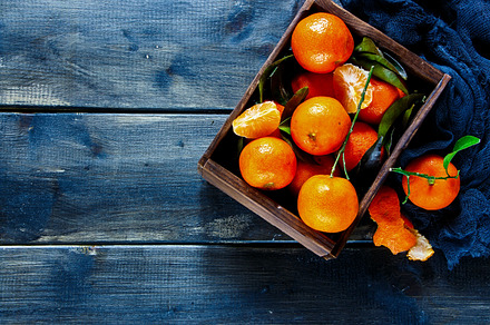 Wooden box of tangerines stock photo containing foods and leaves, a Food & Drink Photo by Yuliya Gontar