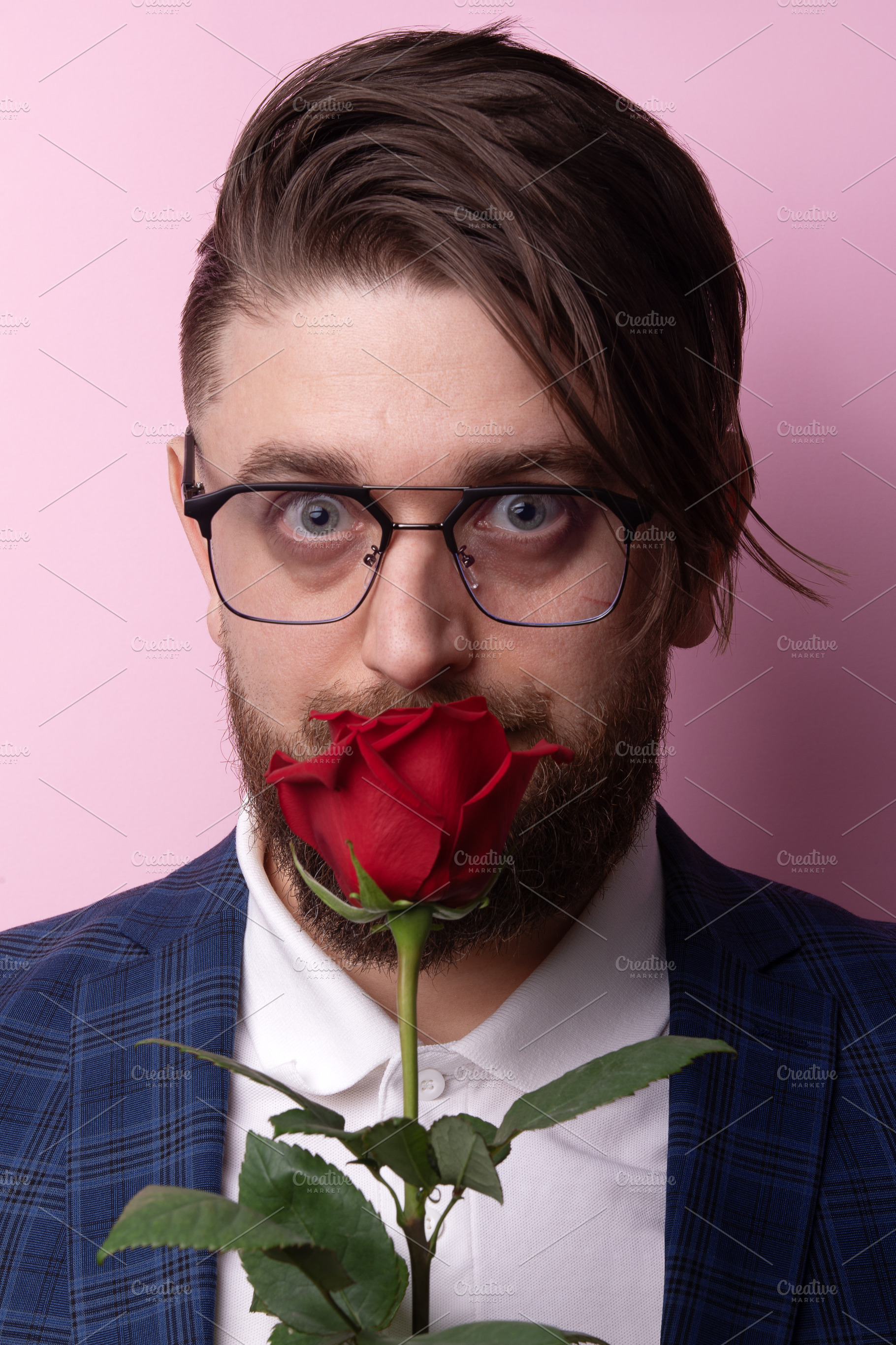 Bearded man in glasses holding red rose in front of face, wearin, a Person Photo by Ales Munt