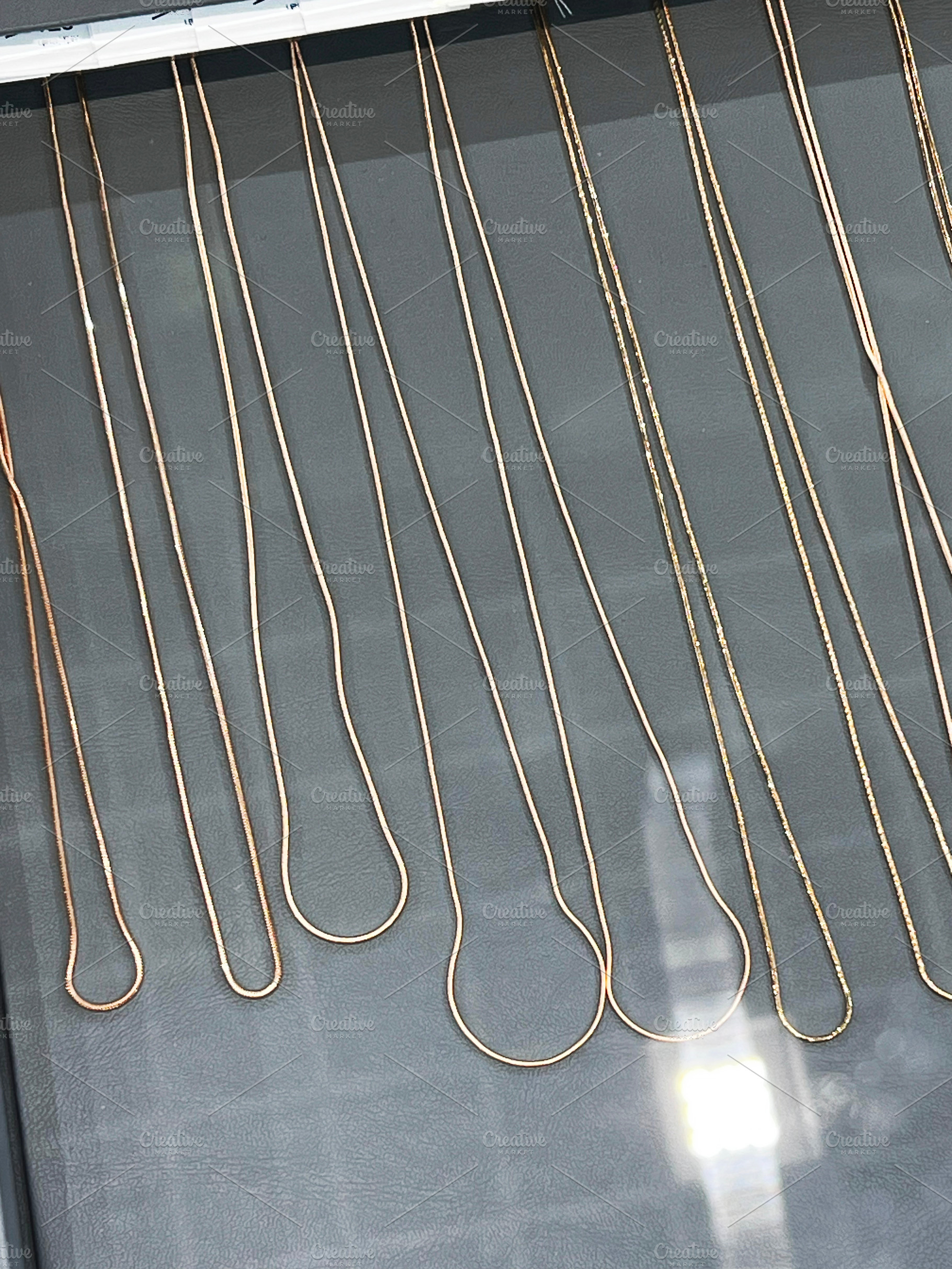 Various gold chains neatly displayed on a jewelry store showcase surface., a Photo by AS photostudio