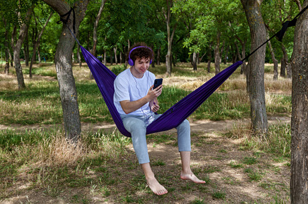 A young guy with curly hair is relaxing on a hammock on a hot summer day., a Person Photo by Photostock