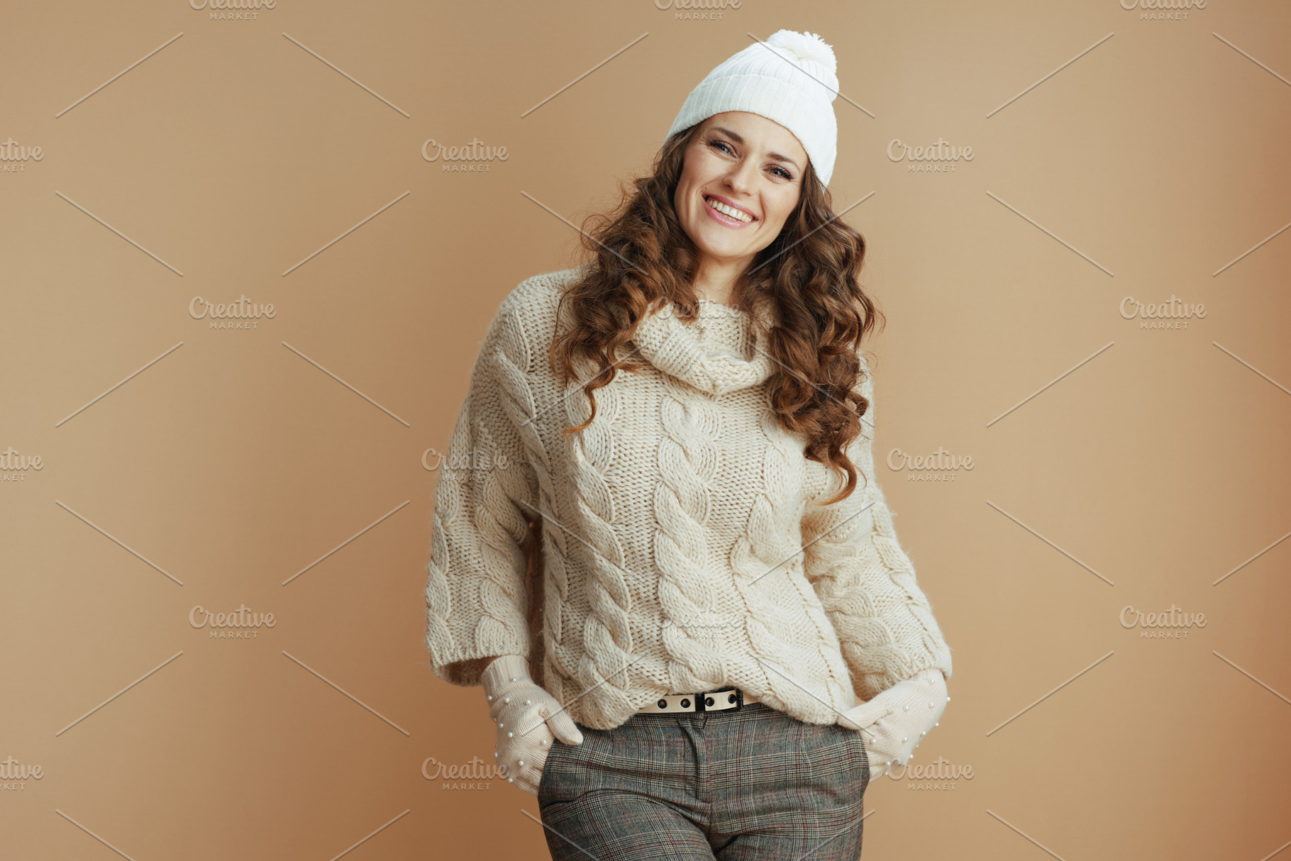 Portrait of smiling woman in beige sweater, mittens and hat, a Person Photo by Alliance Images
