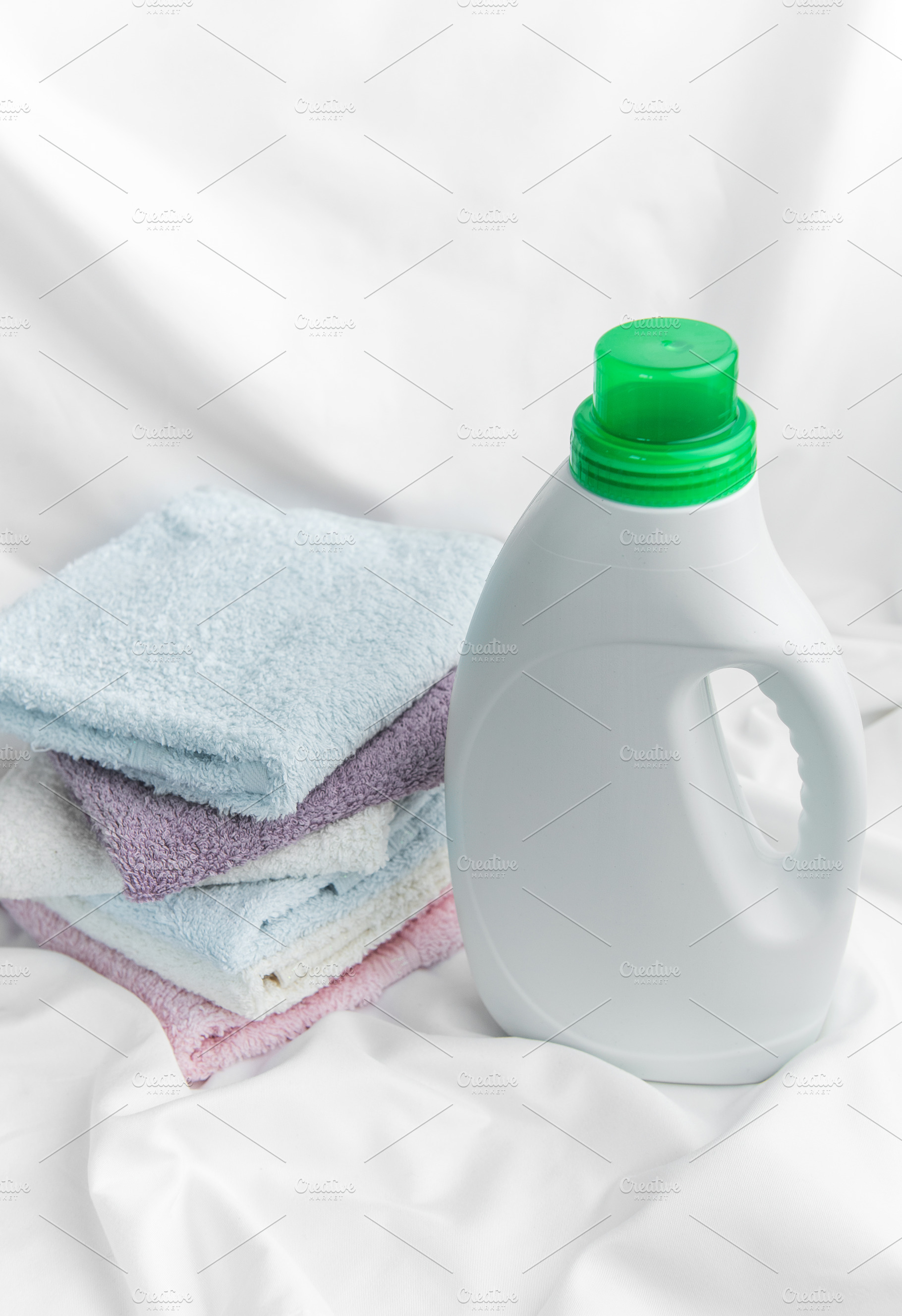 Laundry detergent bottle with clean folded towels, an Industrial Photo by Olena Rudo