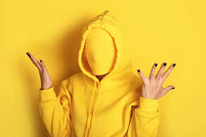 Unrecognizable figure in a yellow sweatshirt with covered face,, a Person Photo by Ales Munt