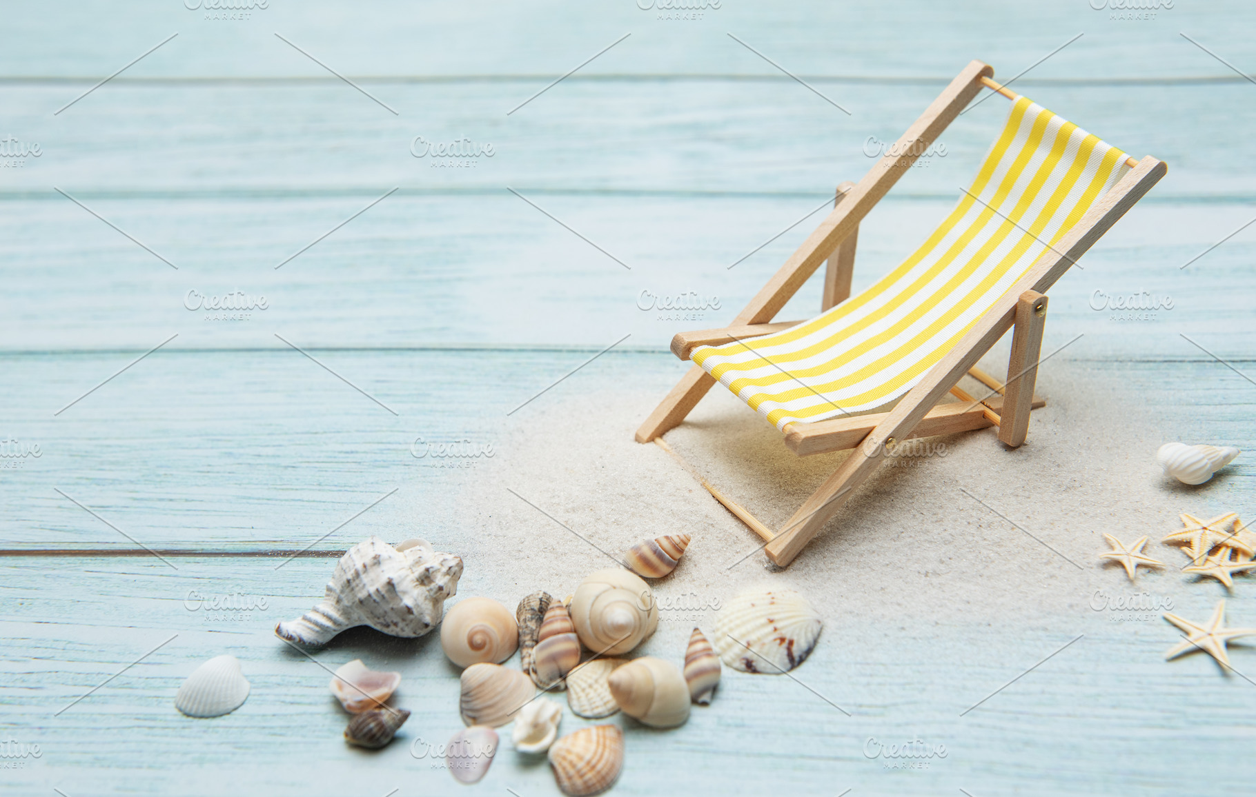 Miniature deck chair on sandy beach with seashells inviting rela, a Holiday Photo by Olena Rudo