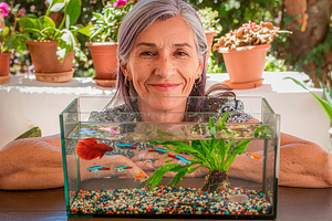 Mature woman posing with aquarium on a sunny balcony, a Person Photo by DanFLCreativo