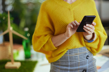 Trendy business owner woman in green office using smartphone, a Photo by Alliance Images