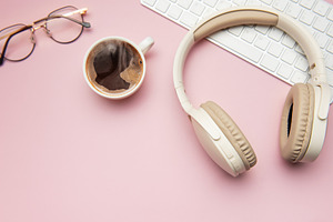 Coffee break accessories on pink table, headphones, keyboard and, a Business Photo by Olena Rudo
