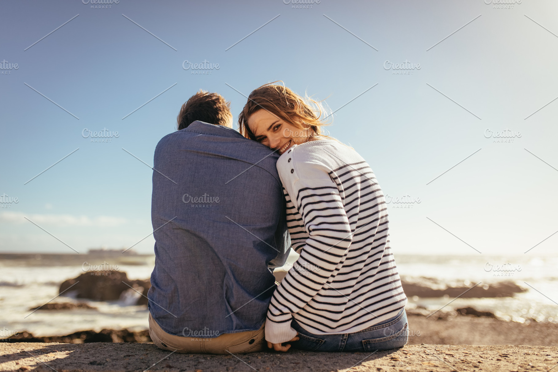 Couple sitting on a sea wall, a Person Photo by Jacob Lund