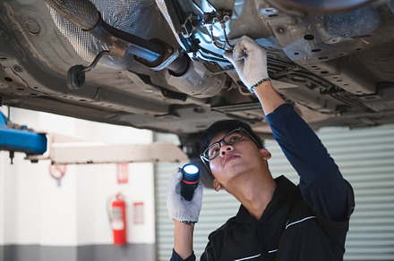 Asian male mechanical hold and shining flashlight to examine car, an Industrial Photo by Ministocker
