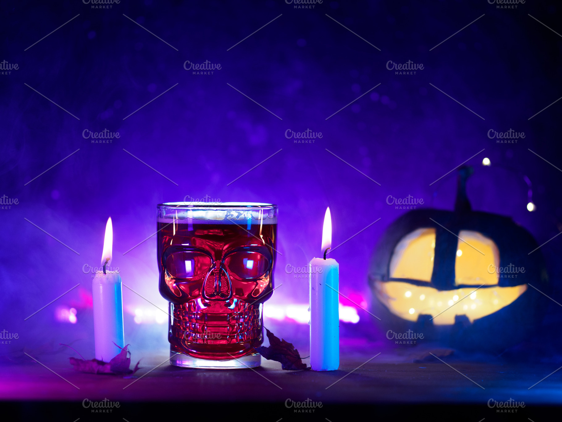 Halloween party concept. A glass of bloody red beer, burning candles and a glow, a Holiday Photo by PavelKant