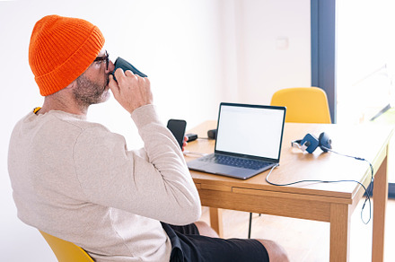 Man working from home on a laptop sitting at a desk surfing the internet and dr, a Person Photo by karrastock
