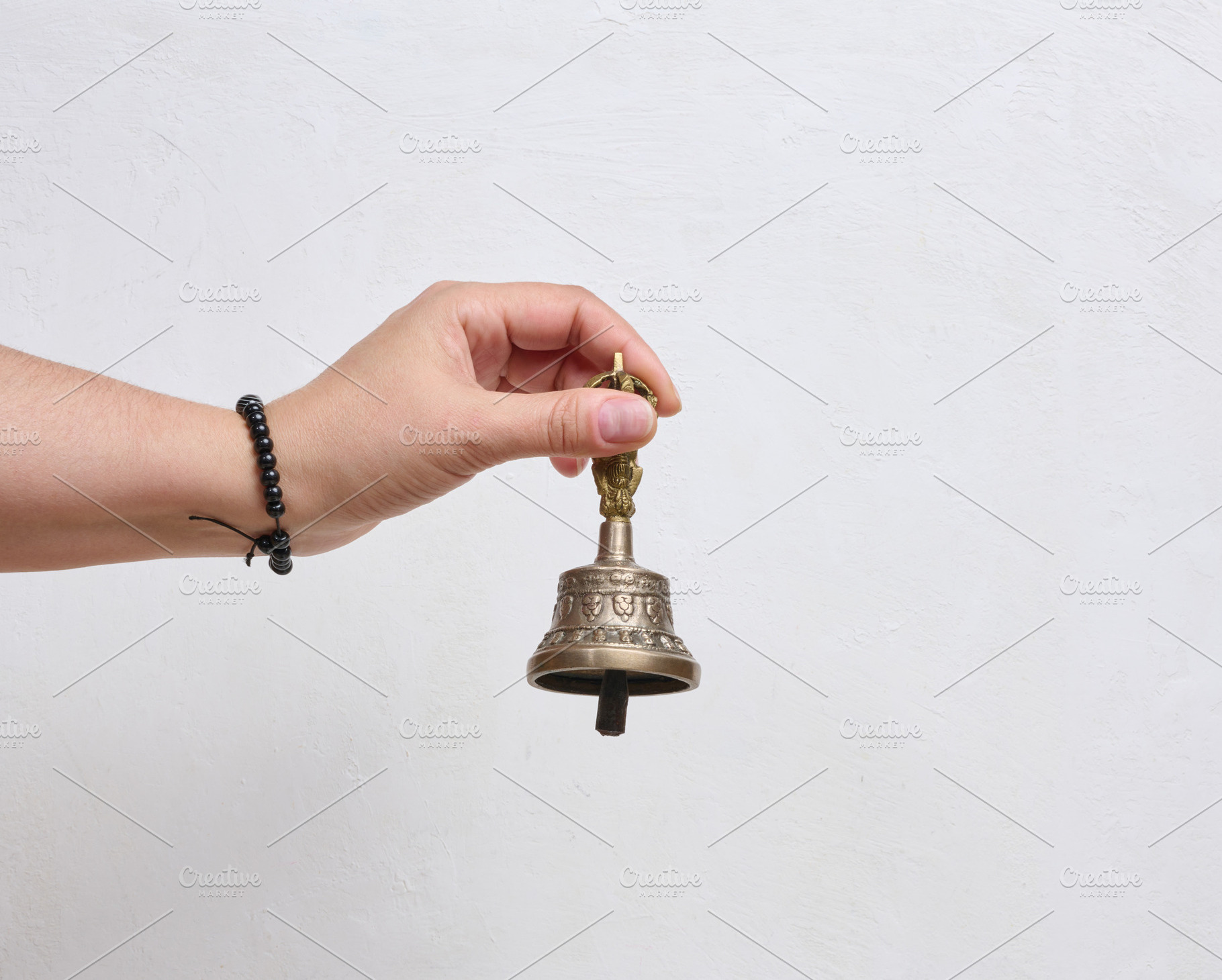 A person holding a traditional Tibetan bronze bell in their hand, a Person Photo by ndanko