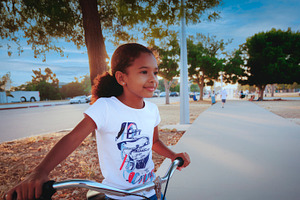 Young girl riding bicycle in city park, a Person Photo by DanFLCreativo