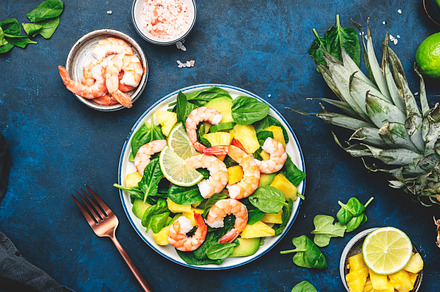 Pineapple salad with shrimps, spinach, avocado and lime on blue, a Food & Drink Photo by 5PH