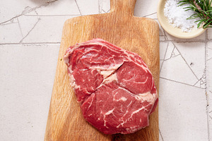 Raw rib-eye steak on wooden cutting board with spices and herbs ready for cooki, a Food & Drink Photo by Asya Nurullina