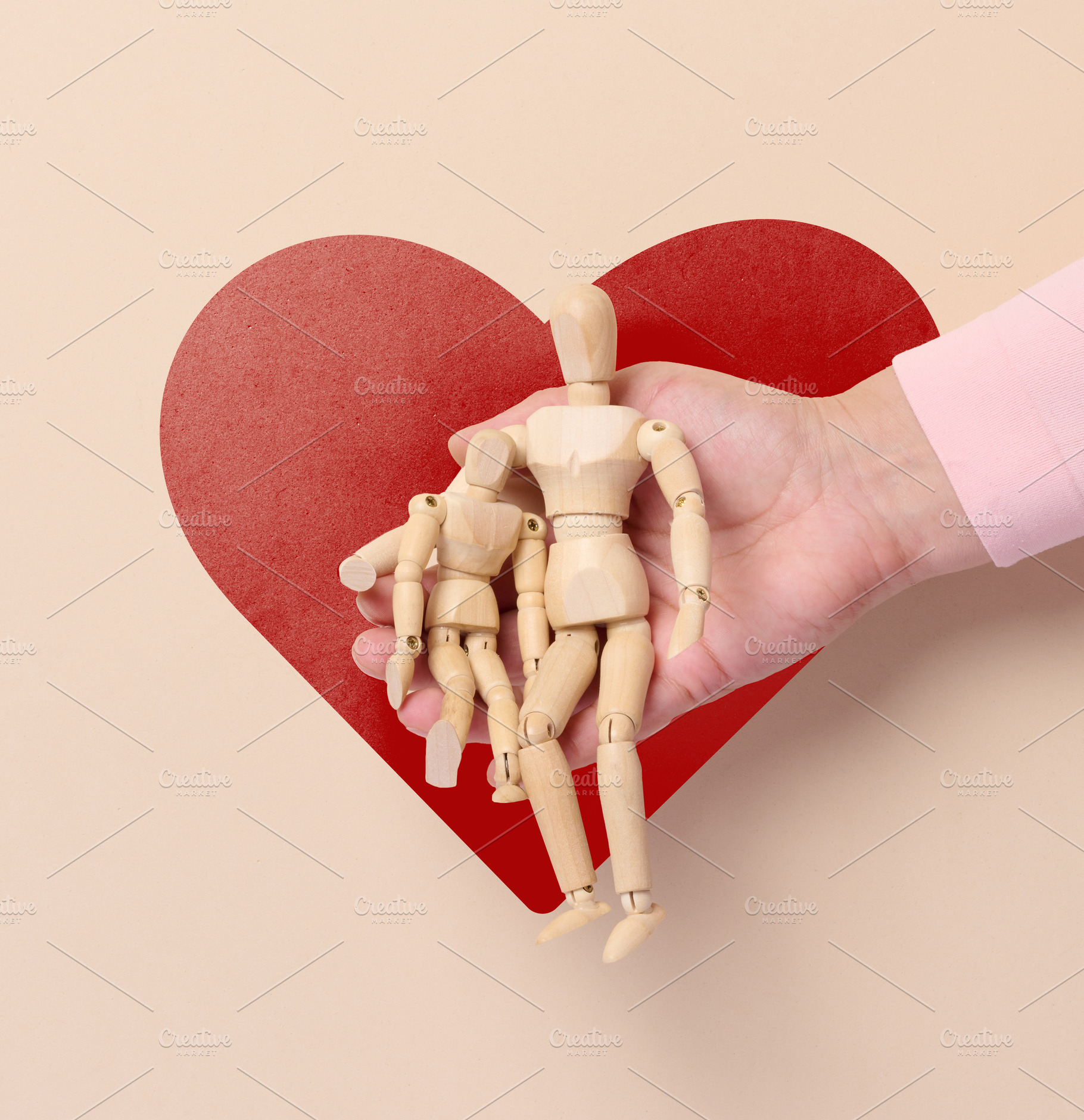 Wooden articulated figures in a person's open palm, with a large, a Holiday Photo by ndanko