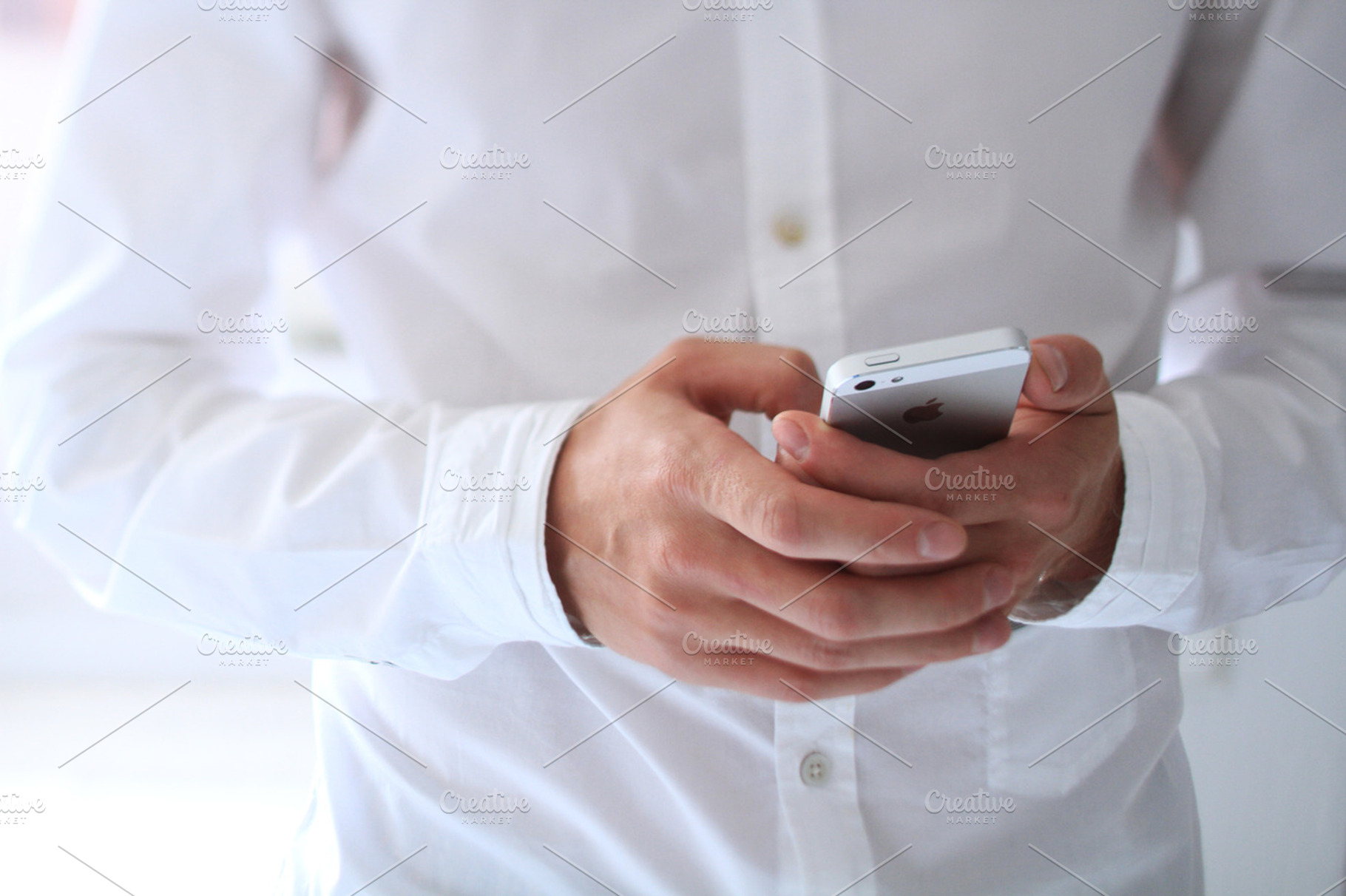 Iphone 5 with male hands containing iphone, white, and hands