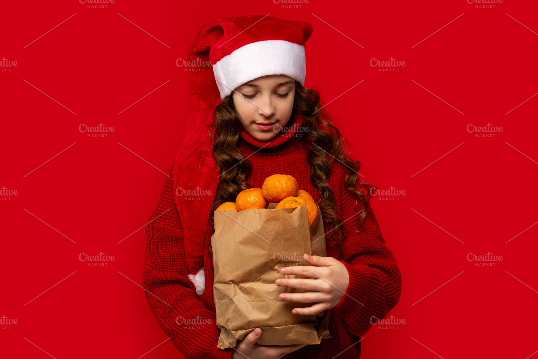 Girl in Santa hat holds paper bag, a Person Photo by Elena Vagengeim