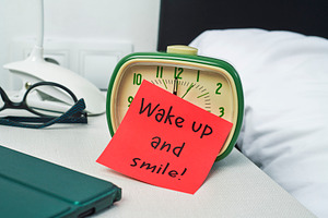 a red note leaning on a green bedside alarm clock, a Photo by Nito
