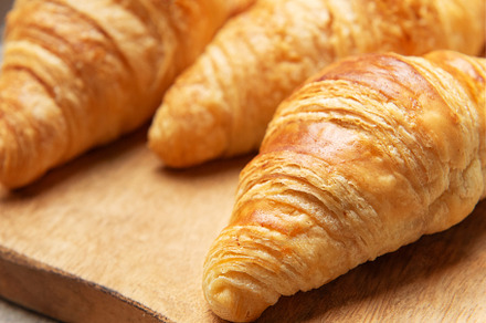 Freshly baked croissants resting on wooden cutting board