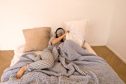 Woman lying in bed covering eyes, a Health & Medical Photo by Elena Vagengeim