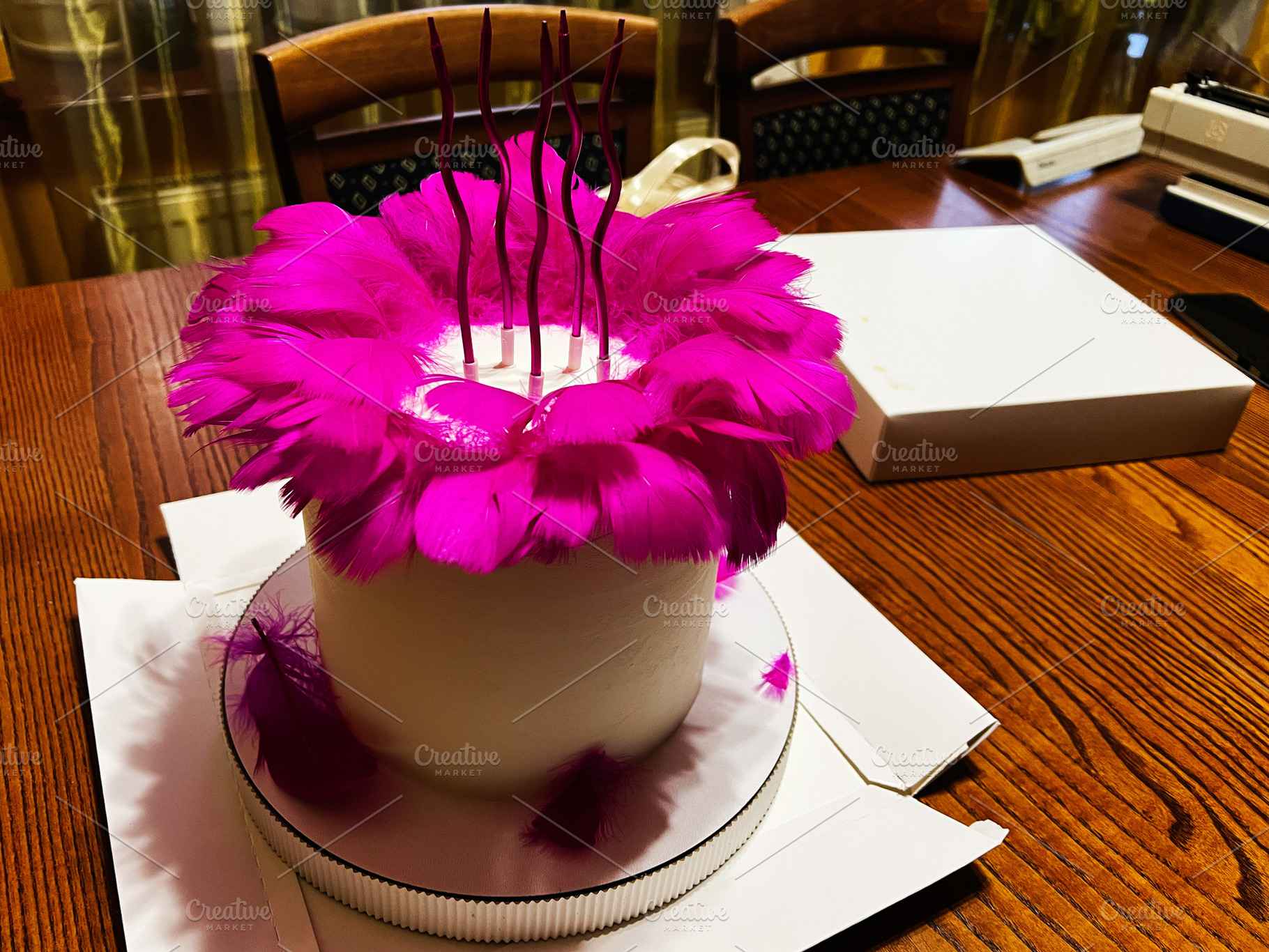 White cake adorned with vibrant pink feathers in decorative presentation, a Photo by AS photostudio