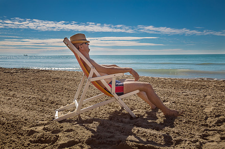 Man in hat relaxing on beach lookin containing background, family, and man, a Nature Photo by Rodica Ciorba