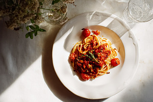 Lunch on a table, pasta with tomato sauce, cherry tomatoes, and, a Photo by Studio ANNA